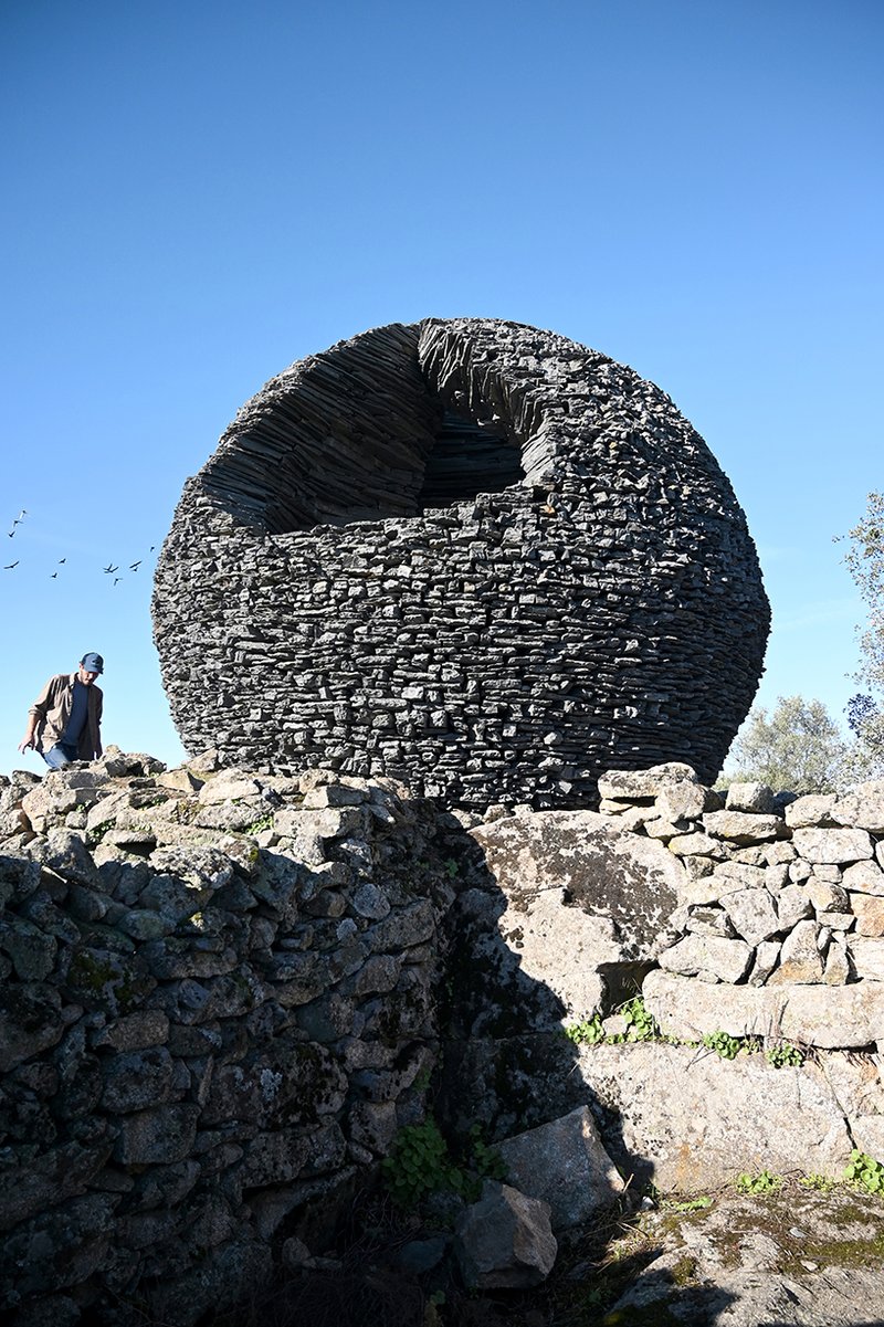 atelier yokyok sculpts sphere land installation out of black schist and granite in portugal